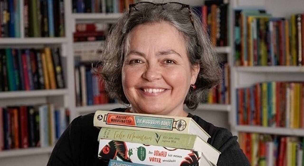 Ein Porträtfoto von Tina Kemnitz, die einen Stapel Bücher trägt