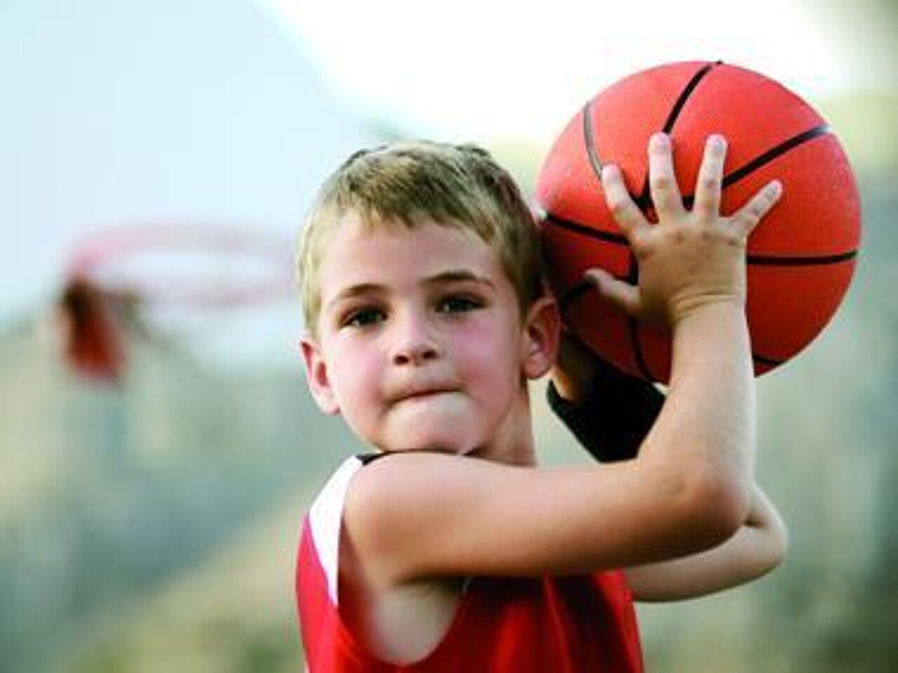 Ein Junge hat einen Basketball in den Händen und täuscht an, diesen zu werfen
