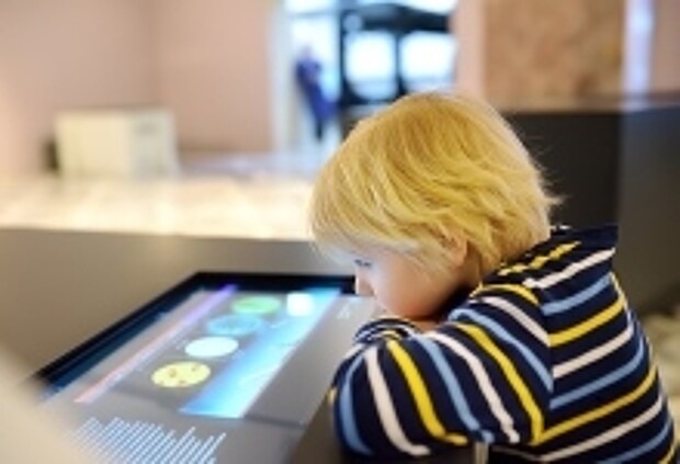 Junge schaut auf Touchscreen im Museum.