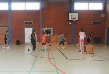 Kinder in einer Sporthalle mit Hockeyschlägern in den Händen.