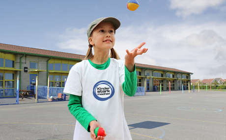 Mädchen in im „Kinder stark machen“-T-Shirt jongliert mit Bällen vor der Schule
