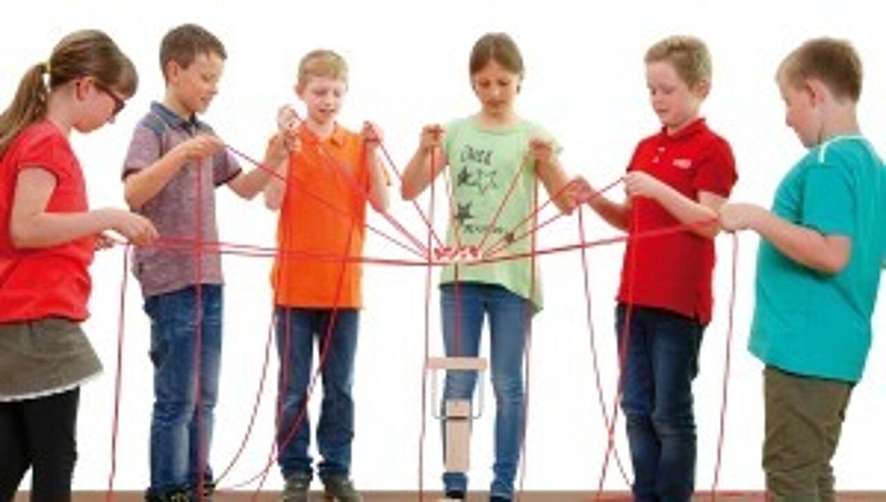 Sechs Kinder führen die Seile, um den Teamturm aufzubauen.