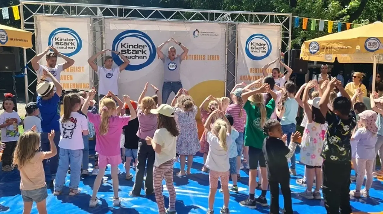 Kinder stark machen-Botschafterin Singa tanzt auf der Bühne. Die Kinder davor mit ihr.