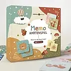 Bild des Memospiel-Kartons mit buntem Design und verstreuten Spielkarten daneben