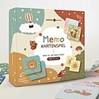 Bild des Memospiel-Kartons mit buntem Design und verstreuten Spielkarten daneben