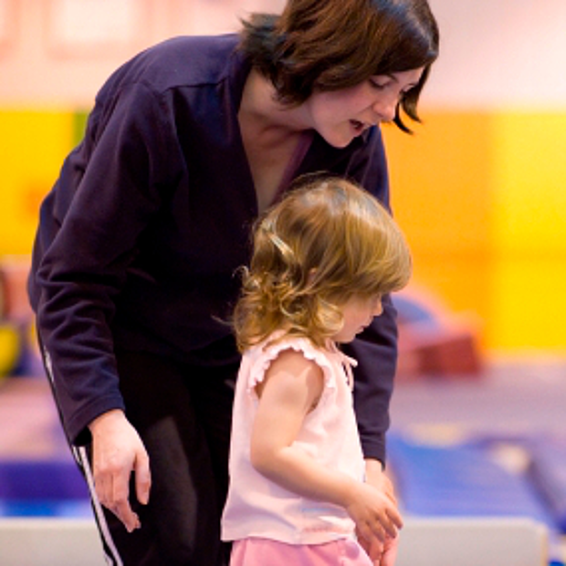 Frau unterstützt Mädchen im Vorschulalter auf dem Balancierbalken