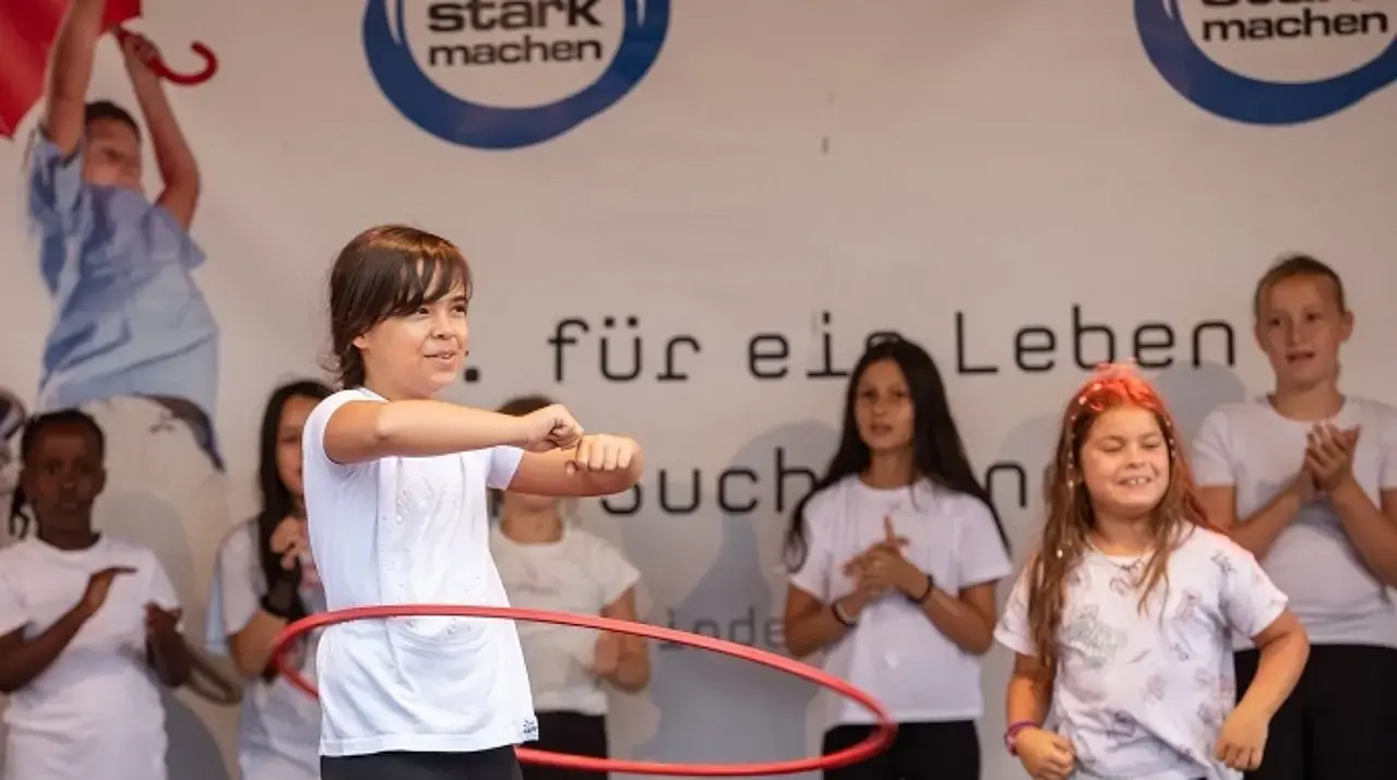 Mädchengruppe beim Hula-Hupp-Spiel auf der Bühne.