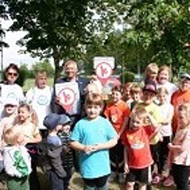 Kinder und Erwachsene stehen um das erste Schild der Bewegungshaltestellen herum