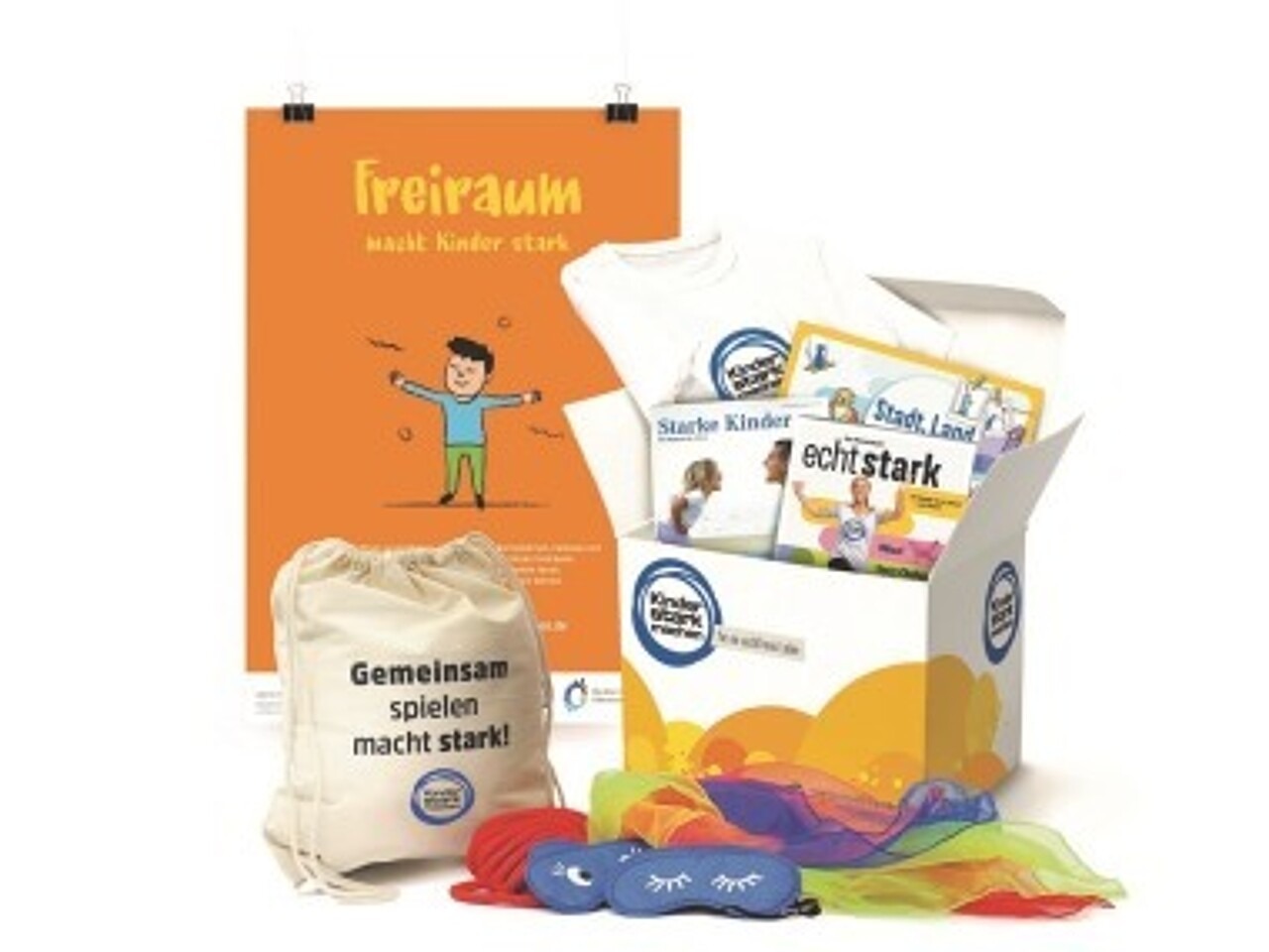 Ansicht eines geöffneten „Kinder stark machen"-Paketes mit Spiele-Set, Mitmachheft „Echt stark“, Geburtstagskalender, Stadt-Land-Spiel-Blöcken und Poster