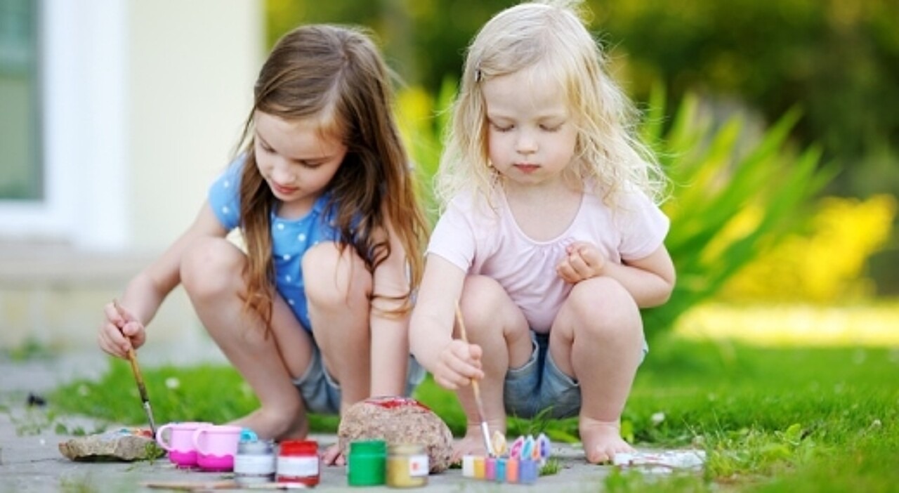 zwei kleine Mädchen bemalen Steine