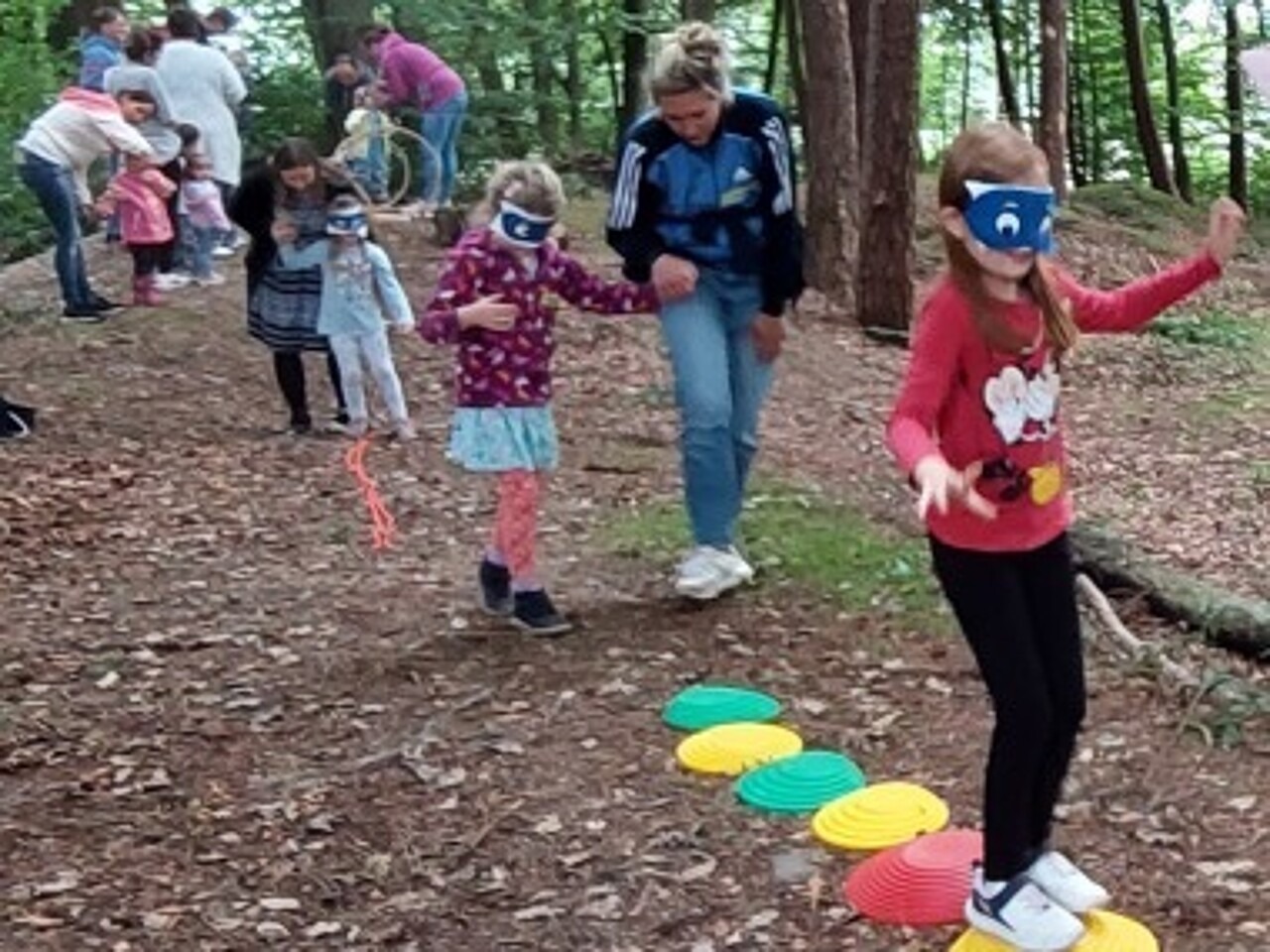 Kinder erproben mit verbundenen Augen den Vertrauensparcours im Wald.