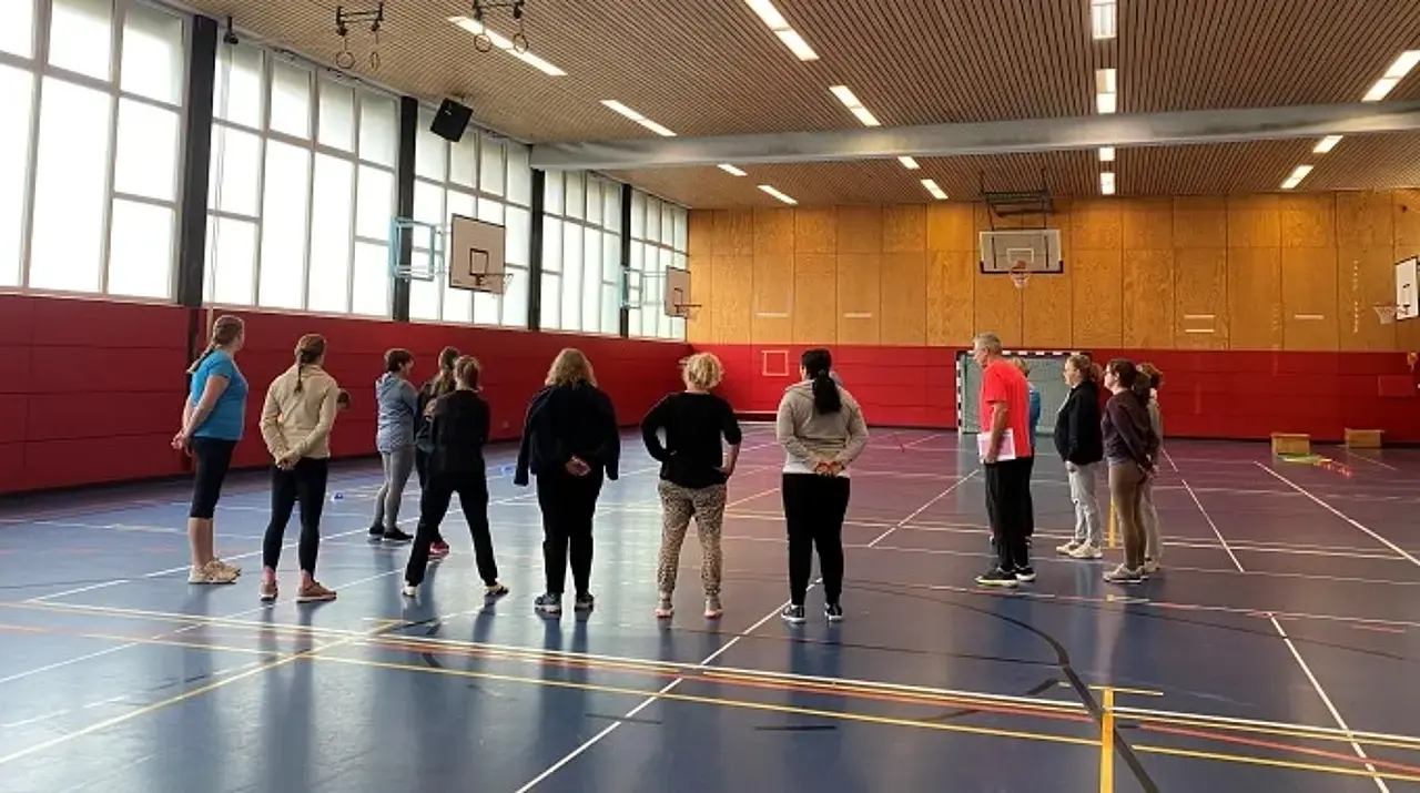 Die Schulungsteilnehmerinnen und -teilnehmer in der Turnhalle lauschen Harald Schmids Erläuterungen.