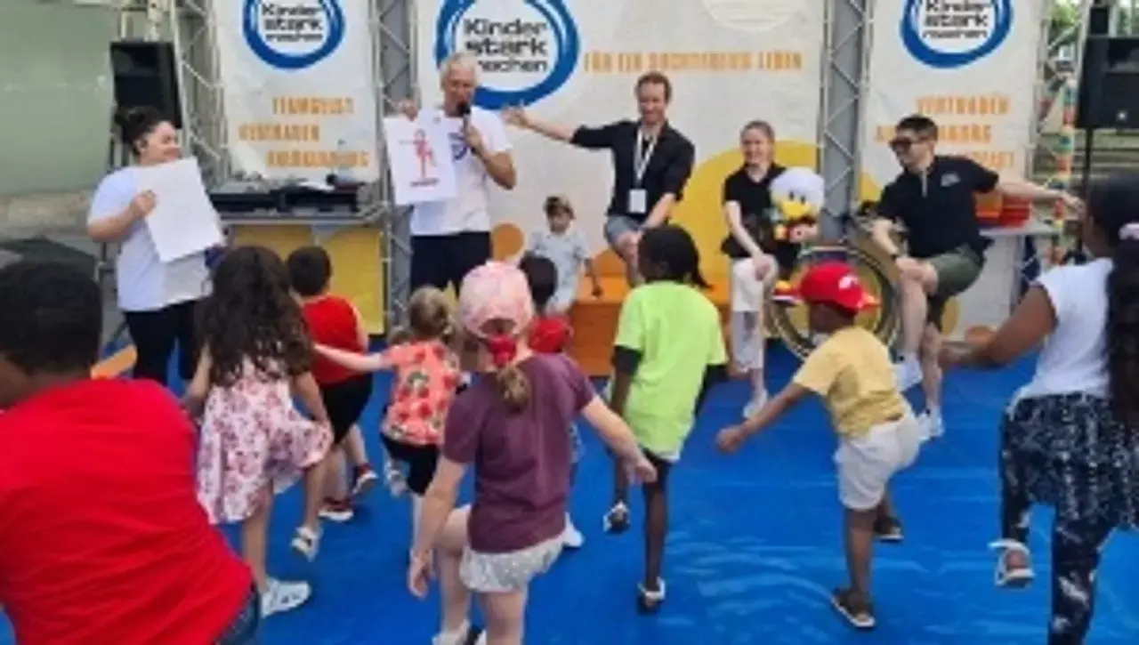 Kinder üben auf der Aktionsbühne die Yoga-Übung Flamingo.
