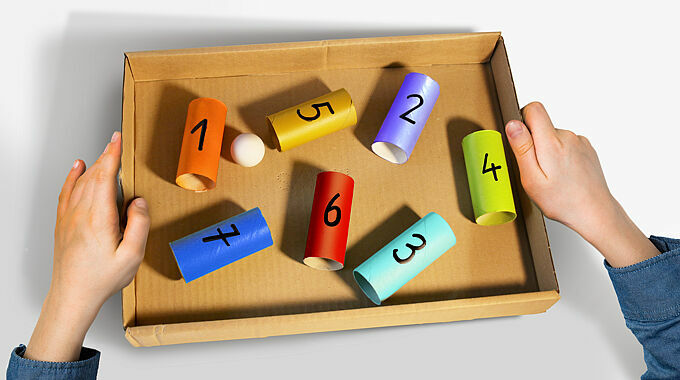 Kartondeckel mit bunt gestalteten, aufgeklebten Toilettenpapierrollen