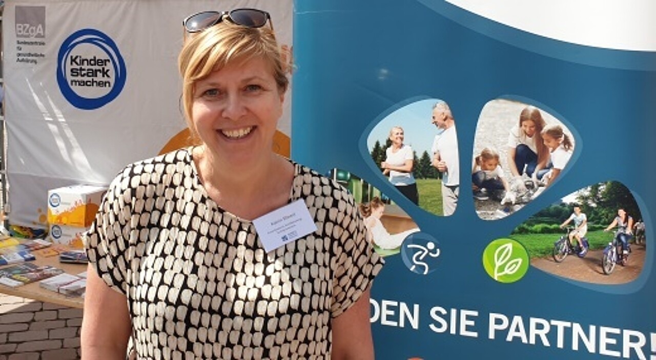 Ein Porträtfoto von Katrin Ehnert vor dem Kinder stark machen-Logo.