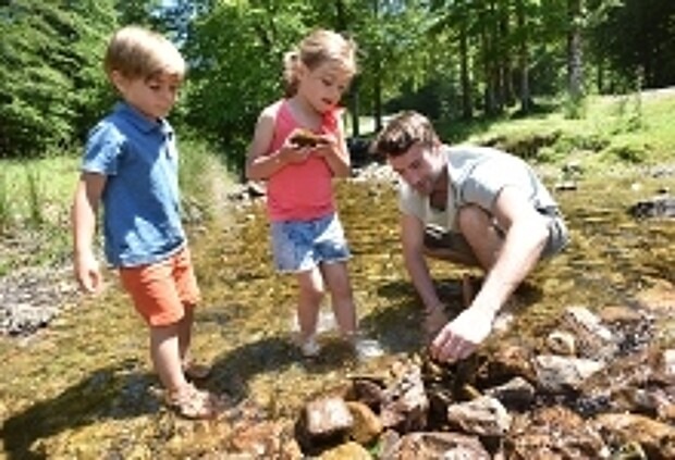 Vater und Kinder bauen mit Steinen Staudamm.