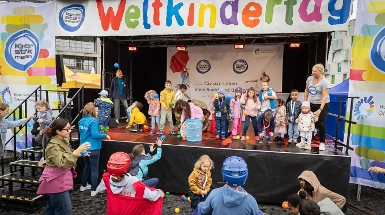 Singa spielt mit den Kindern auf und vor der BIÖG-Bühne ein Ballwurf-Spiel.