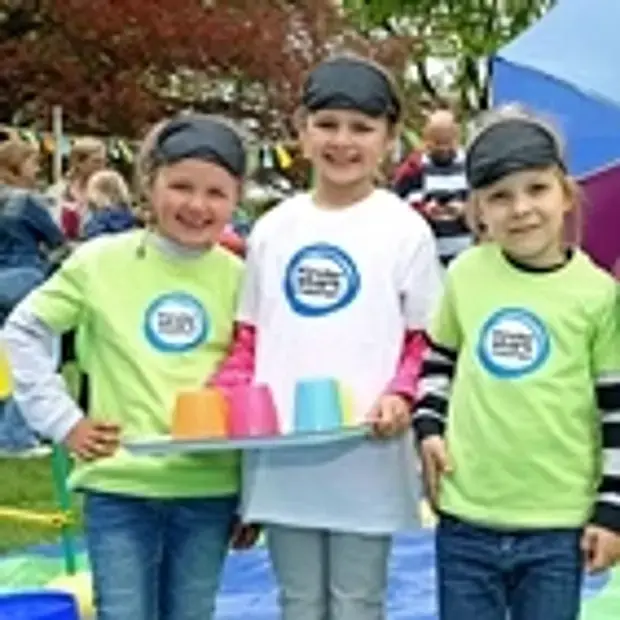 Drei Mädchen auf dem Vertrauensparcours in bunten T-Shirts mit dem „Kinder stark machen“-Logo