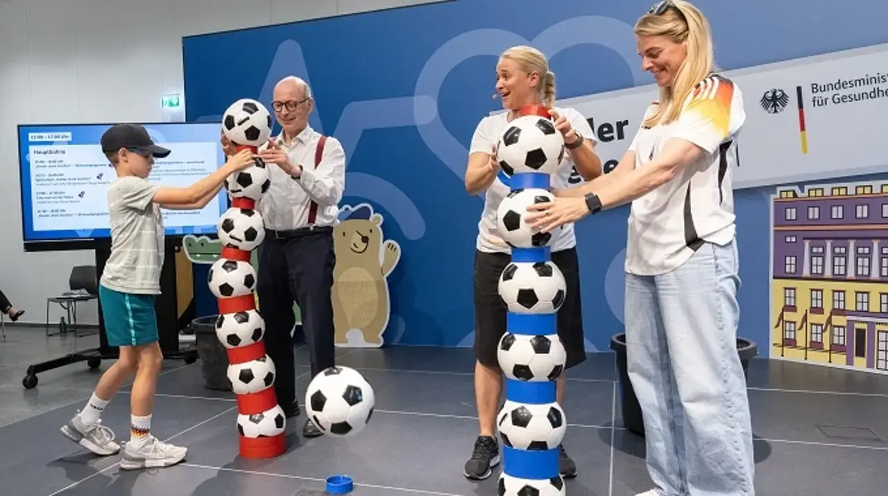 Die Botschafterinnen Nia und Singa wetteifern mit Dr. Nießen und einem Kind um den höchsten Bälleturm.