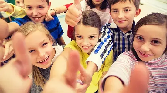Eine Gruppe gut gelaunter Kinder, die das Daumen-Hoch-Zeichen machen.