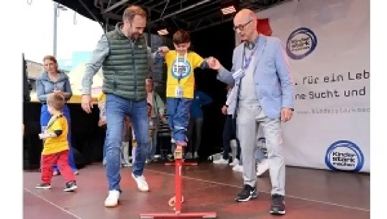 Robert Voigtsberger und Dr. Johannes Nießen reichen einem Jungen beim Balancieren eine helfende Hand.