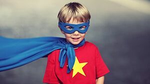 Junge mit einem roten T-Shirt mit gelbem Stern trägt eine blaue Maske und einen blauen Umhang