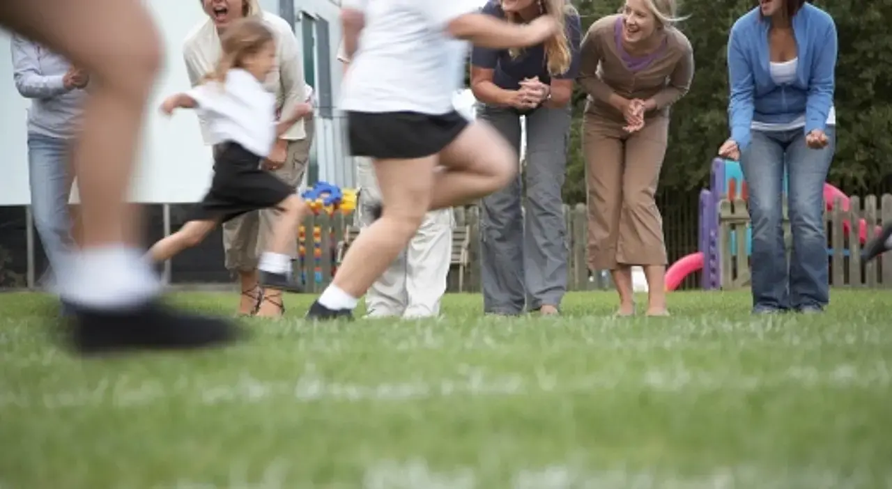 Kinder im Grundschulalter bei einem Rennen werden von ihren Eltern angefeuert