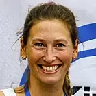 Victoria von Eynatten steht vor einem "Kinder stark machen"-Banner und hält ihr Buch in die Kamera