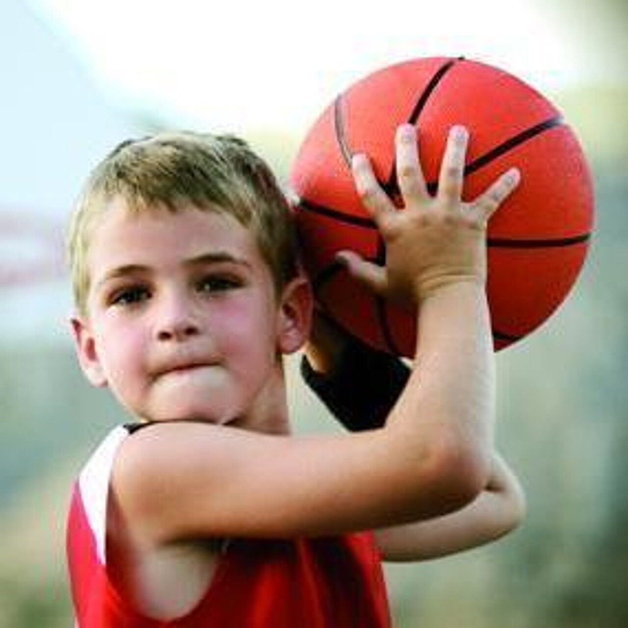 kleiner Junge will einen Basketball werfen