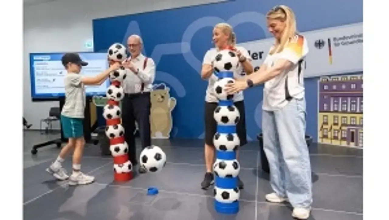 Die Botschafterinnen Nia und Singa wetteifern mit Dr. Nießen und einem Kind um den höchsten Bälleturm.