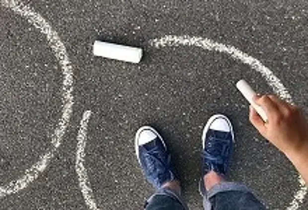 Ein Kind malt einen Kreidekreis auf Asphalt