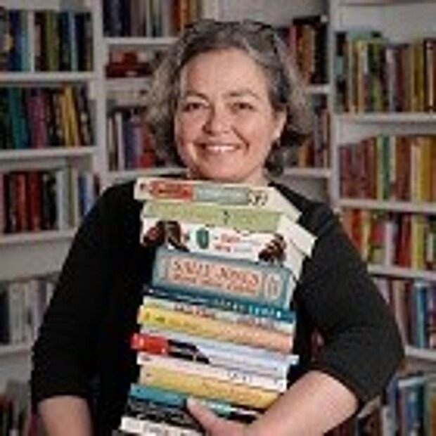 Ein Porträtfoto von Tina Kemnitz, die einen Stapel Bücher trägt
