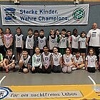 Eine Gruppe Kinder des TSV Achim steht mit ihrem Trainer vor einem "Kinder stark machen"-Banner