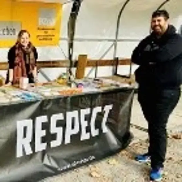 Eine Frau und ein Mann stehen an einem Infostand mit Broschüren
