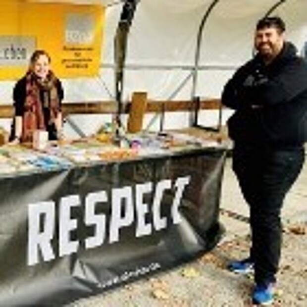 Eine Frau und ein Mann stehen an einem Infostand mit Broschüren