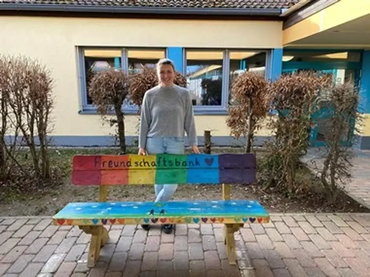 Carolin Hippel hinter der bunt angemalten Freundschaftsbank auf dem Schulhof.