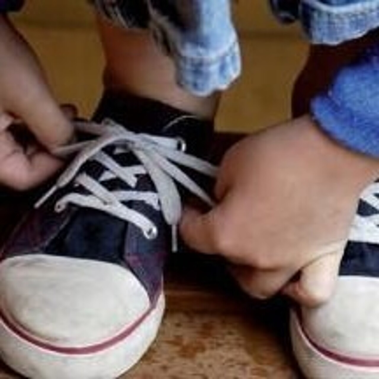 Kind bindet sich die Schuhe zu