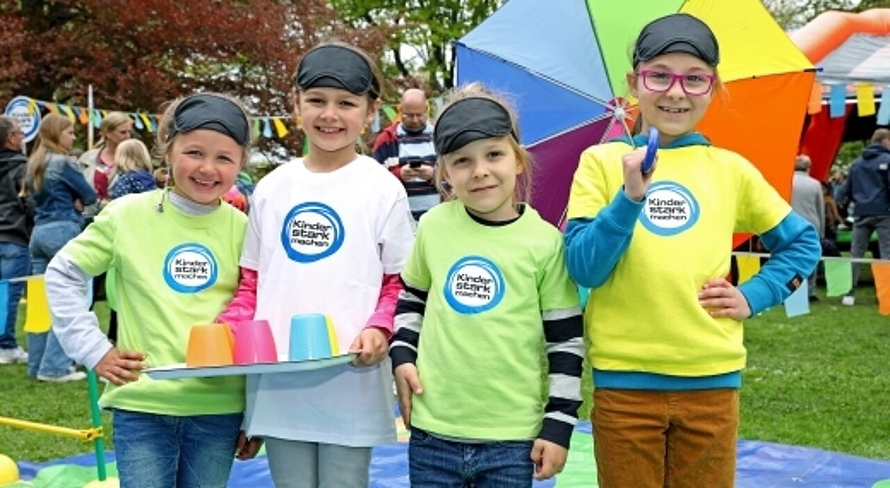 Drei Mädchen auf dem Vertrauensparcours in bunten T-Shirts mit dem „Kinder stark machen“-Logo