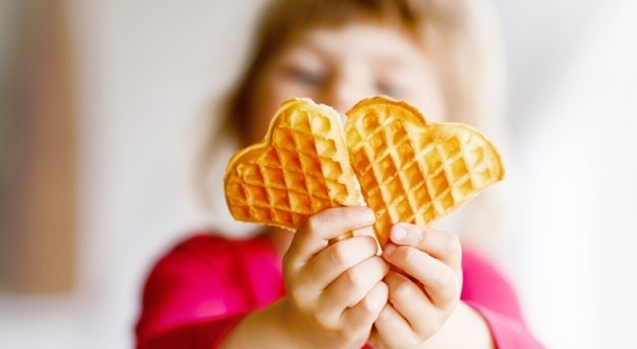 Ein Kind hält eine Waffel in die Kamera