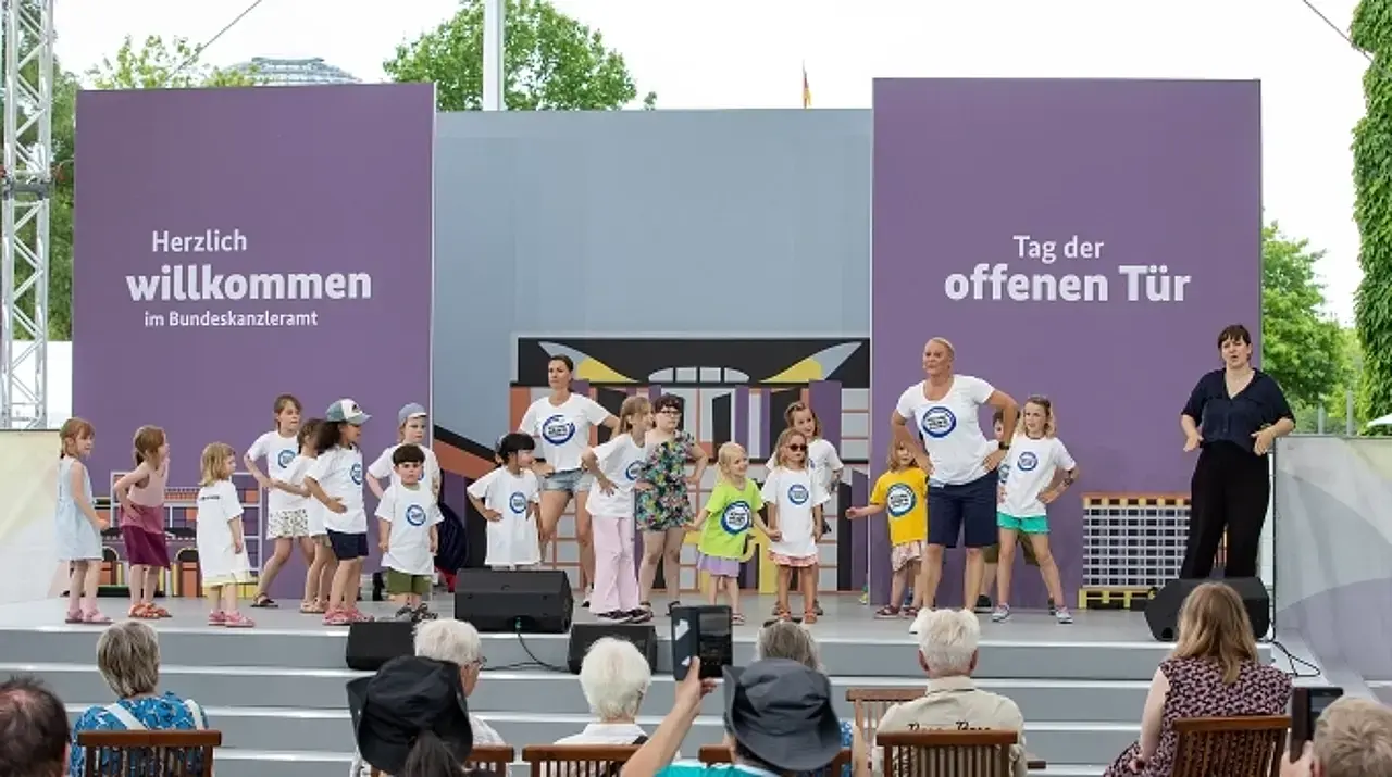 © BIÖG / Carsten Kobow Singa mit Kindern auf der Bühne am Bundeskanzleramt