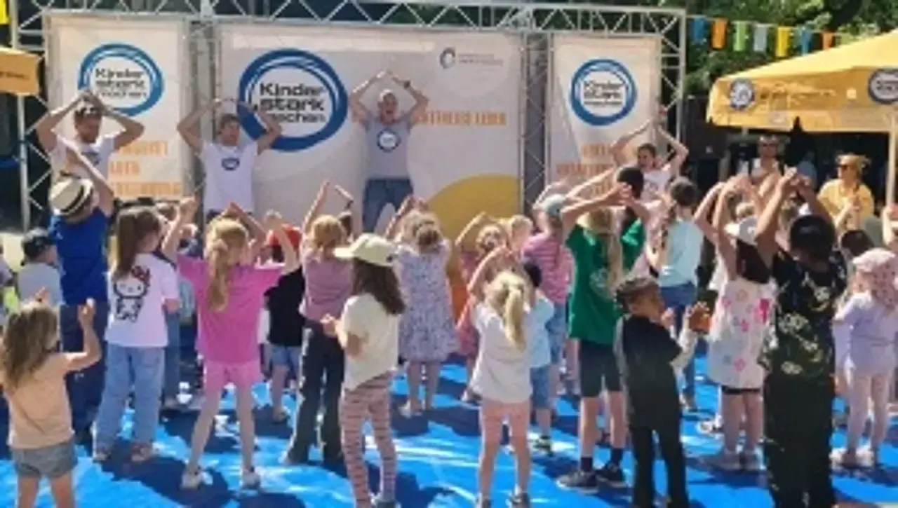 Kinder stark machen-Botschafterin Singa tanzt auf der Bühne. Die Kinder davor mit ihr.