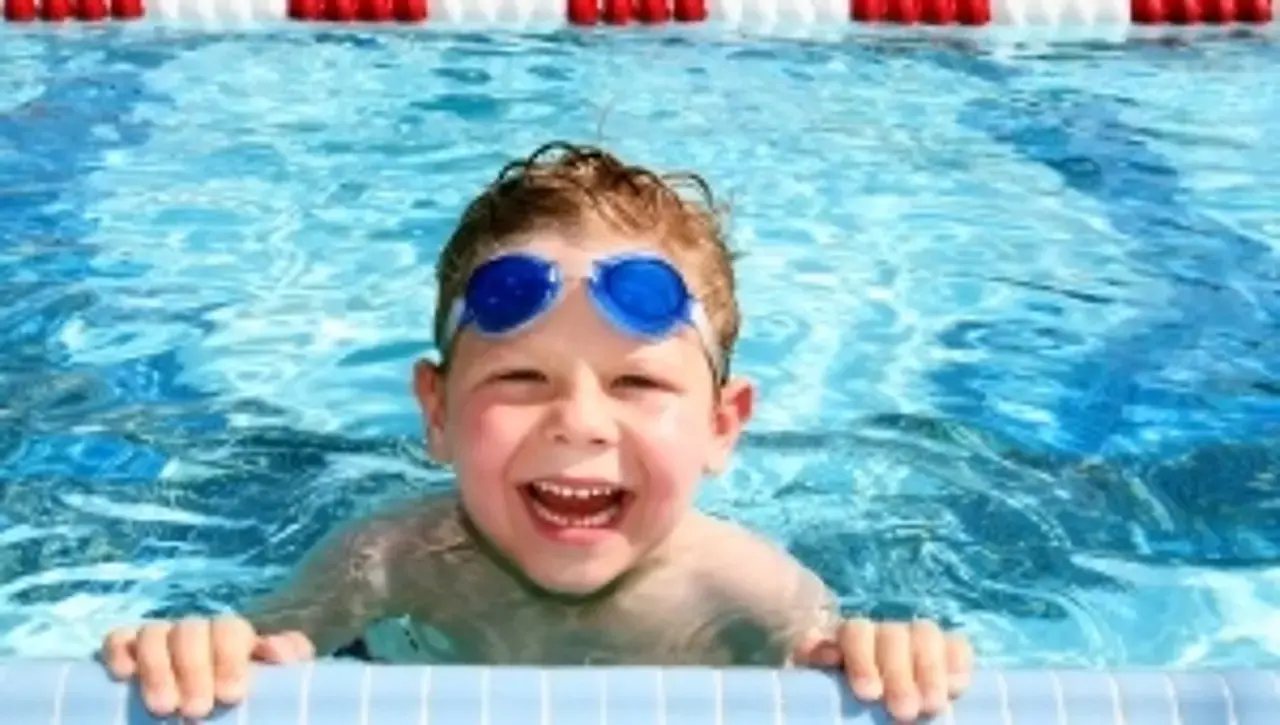 Vor Vergnügen lachender Junge im Freibad.