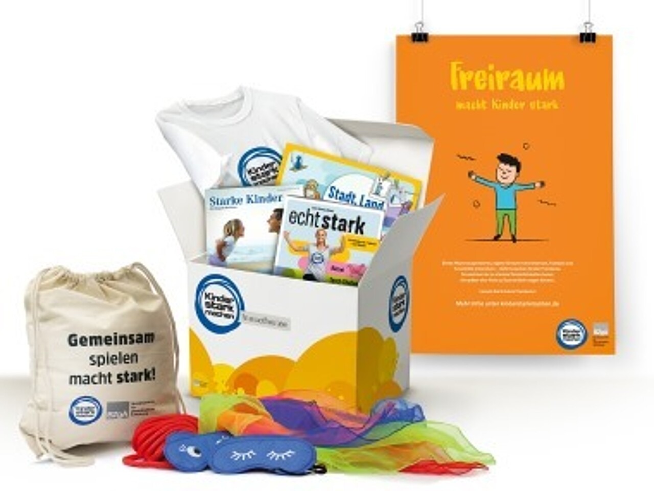 Ansicht eines geöffneten „Kinder stark machen"-Paketes mit Spiele-Set, Mitmachheft „Echt stark“, Geburtstagskalender, Stadt-Land-Tier-Blöcken und Poster
