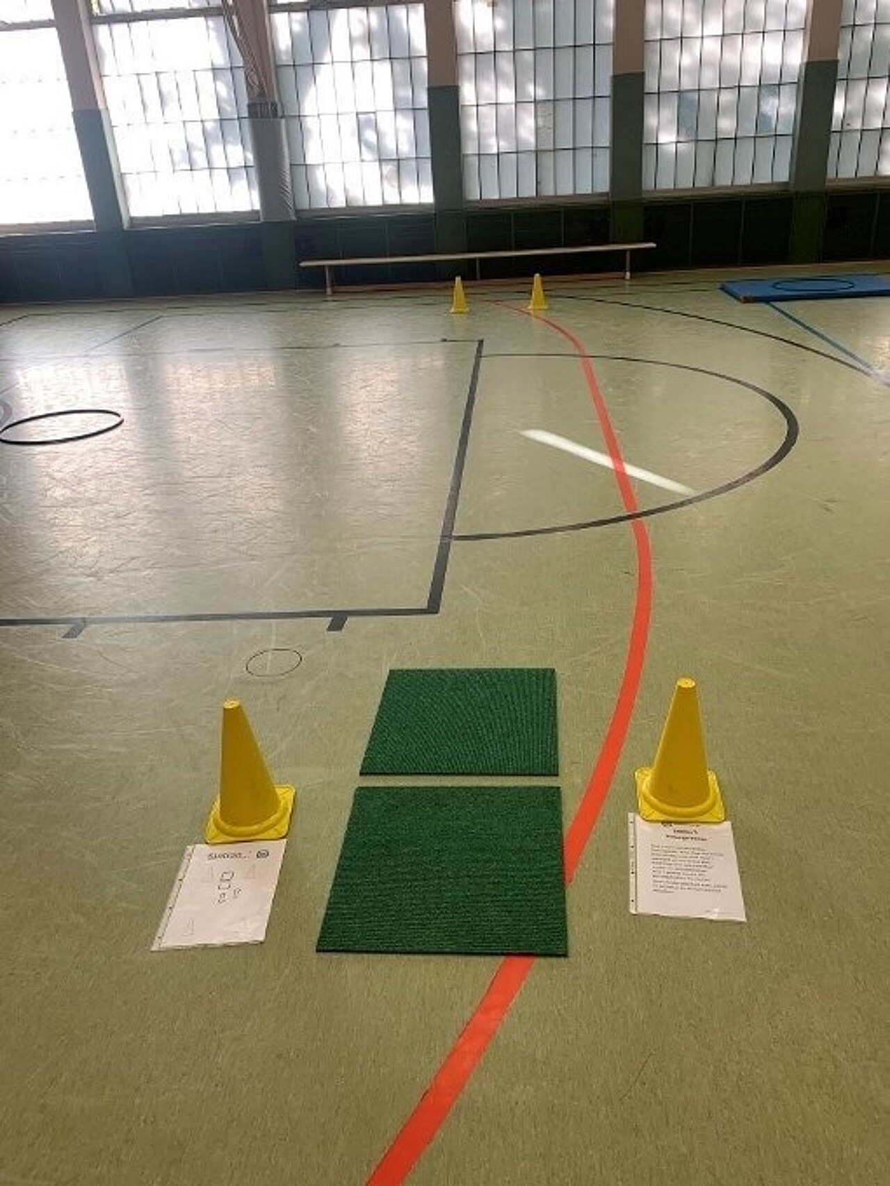 2 Teppichfliesen liegen an der mit Hütchen markierten Start- und Ziellinie. 1 weiteres Hütchen markiert 10m entfernt markiert den Wendepunkt.