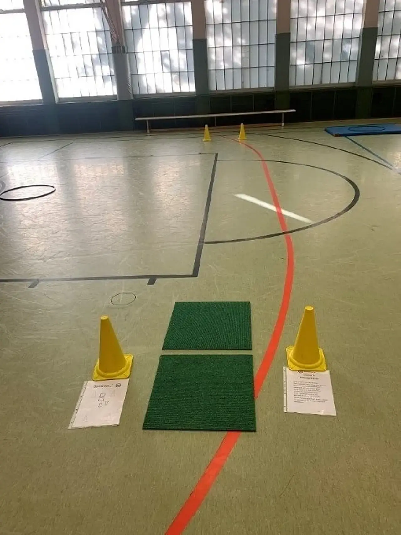 2 Teppichfliesen liegen an der mit Hütchen markierten Start- und Ziellinie. 1 weiteres Hütchen markiert 10m entfernt markiert den Wendepunkt.