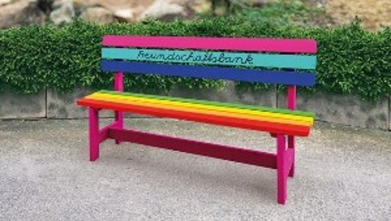 Bunt angemalte Holzbank, die in Schreibschrift den Schriftzug Freundschaftsbank trägt.