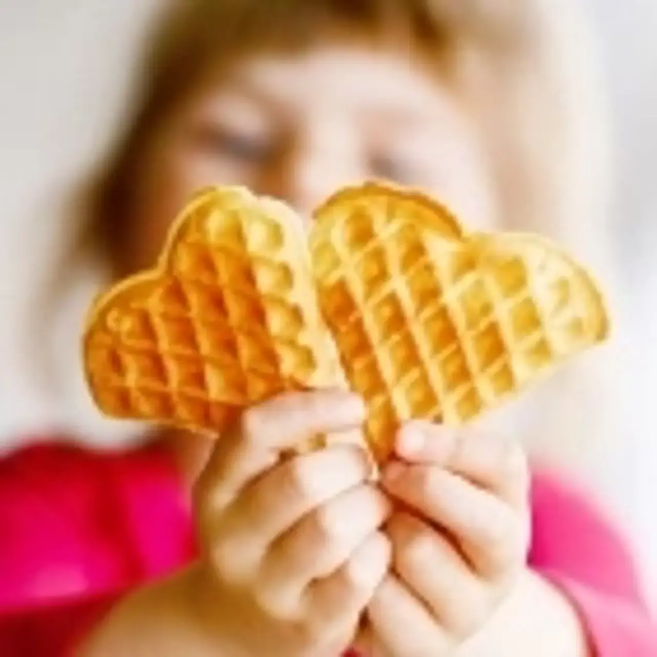 ein Kind hält eine Waffel in die Kamera