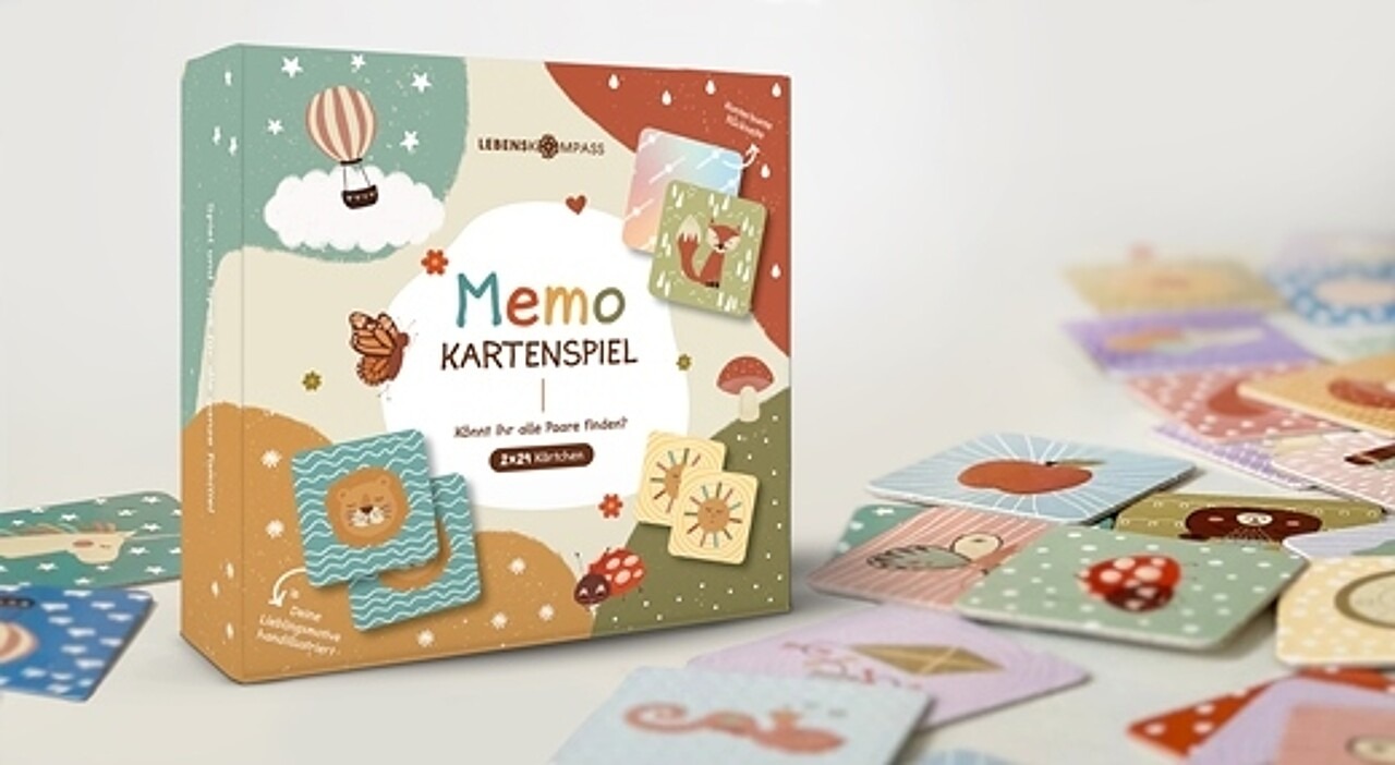 Bild des Memospiel-Kartons mit buntem Design und verstreuten Spielkarten daneben