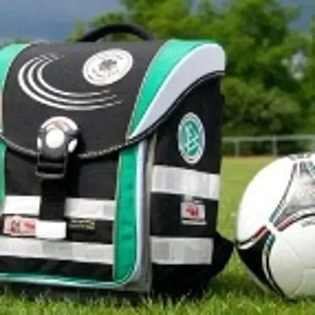Ein Ranzen und ein Fußball auf dem Rasen