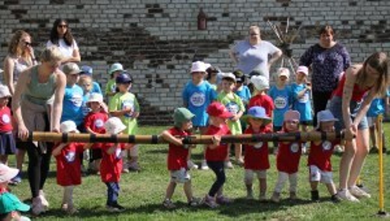 Kita-Kinder und Erzieher beim Baumholzziehen